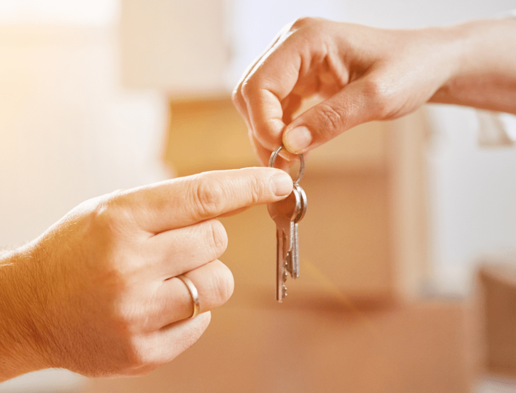 person's hand giving keys to another person's hand